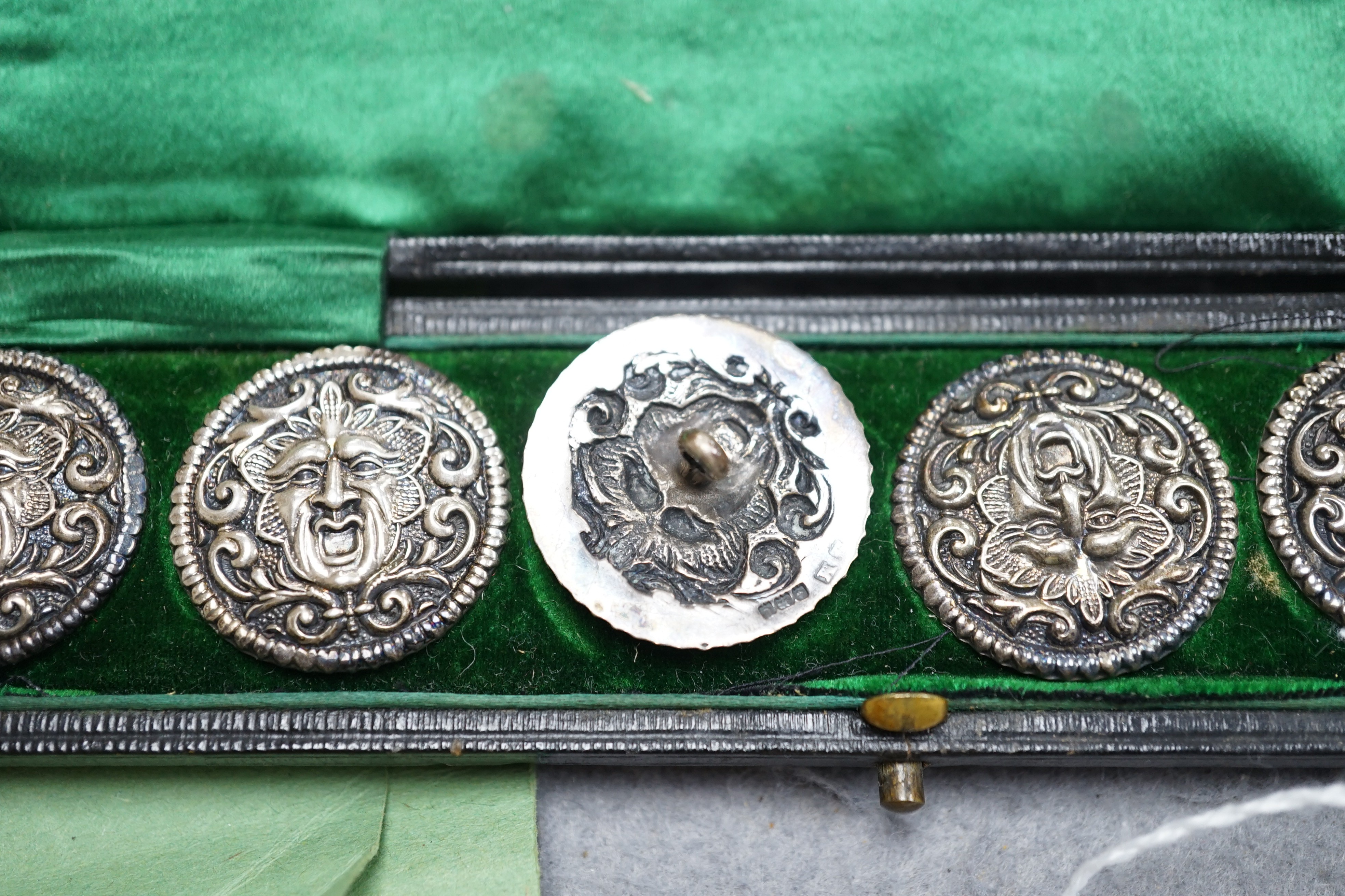 A cased set of six Edwardian silver buttons, each embossed with a mask, Henry Matthews, Birmingham, 1902, 27mm.